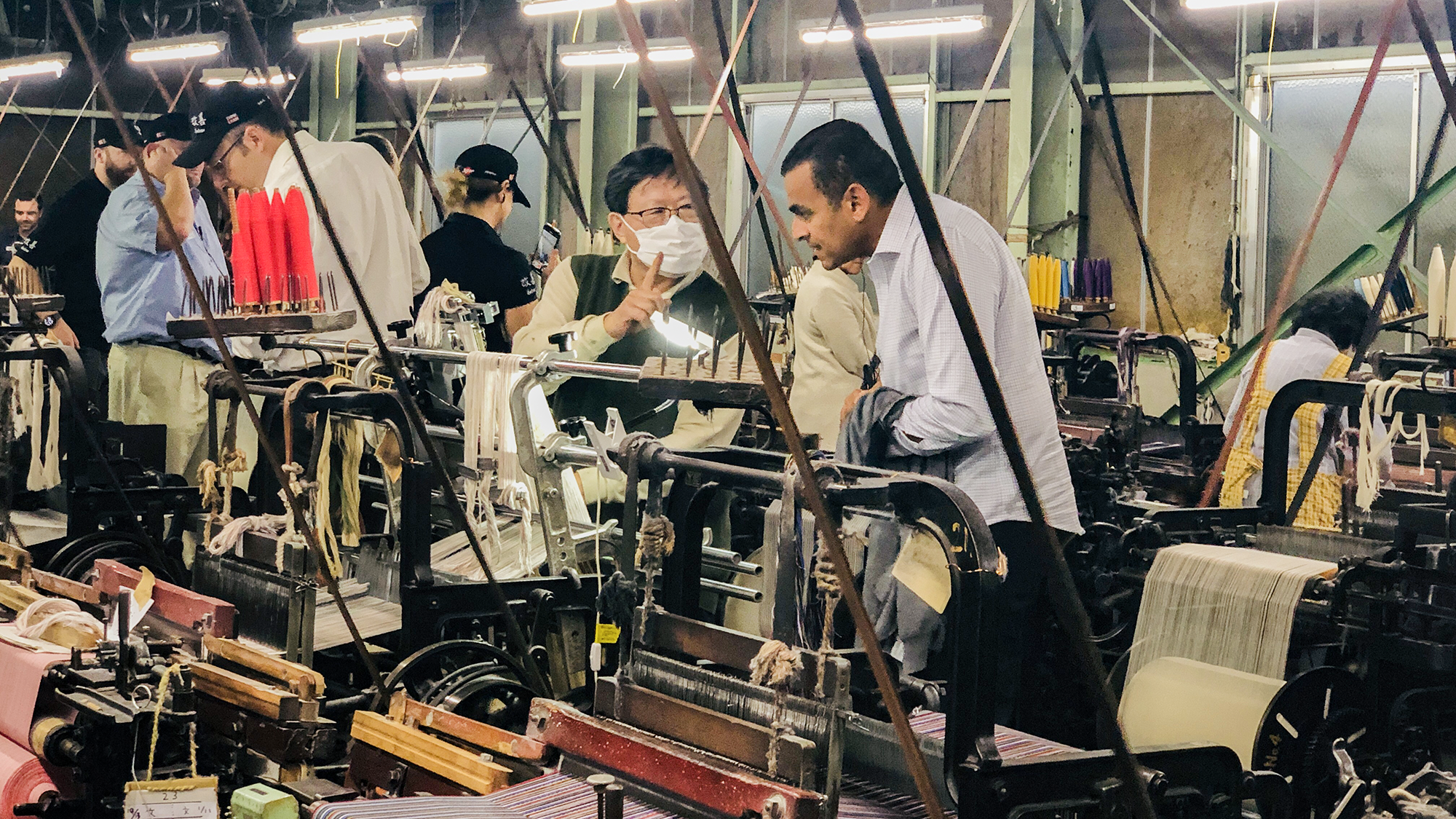 A man receiving an explanation in front of a loom